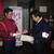　贈呈された裏面広告入りロール紙を受け取る荒井店長。早速、店頭にセットした