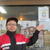 取扱店のポスターを貼りＰＲする深井社長