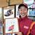 コミックのイラスト入りの色紙を持つ丸野店長。キャップにはＳＳの店名も